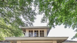 Ein zweistöckiges Haus mit einer Veranda, einer Holztür und der Hausnummer 1412 über der Tür.