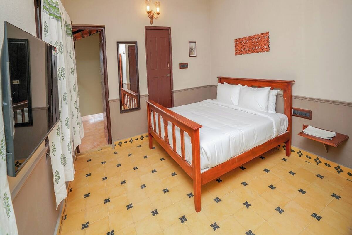 A bedroom with a wooden bed, a ceiling fan, a wall-mounted light fixture, and a small bedside table.