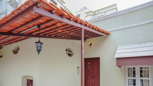 Un edificio con puerta roja, balcón con barandilla blanca y techo de tejas rojas.