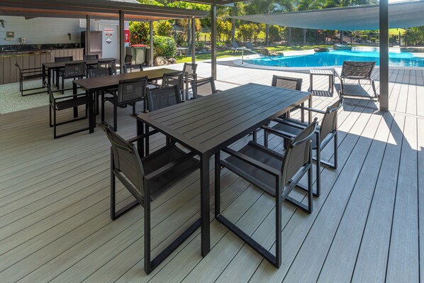 An outdoor patio with a pool, tables, and chairs.