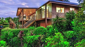 A modern two-story house with a wooden exterior, large windows, and a balcony.