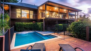 A modern two-story house with a swimming pool, outdoor seating, and a covered patio area.