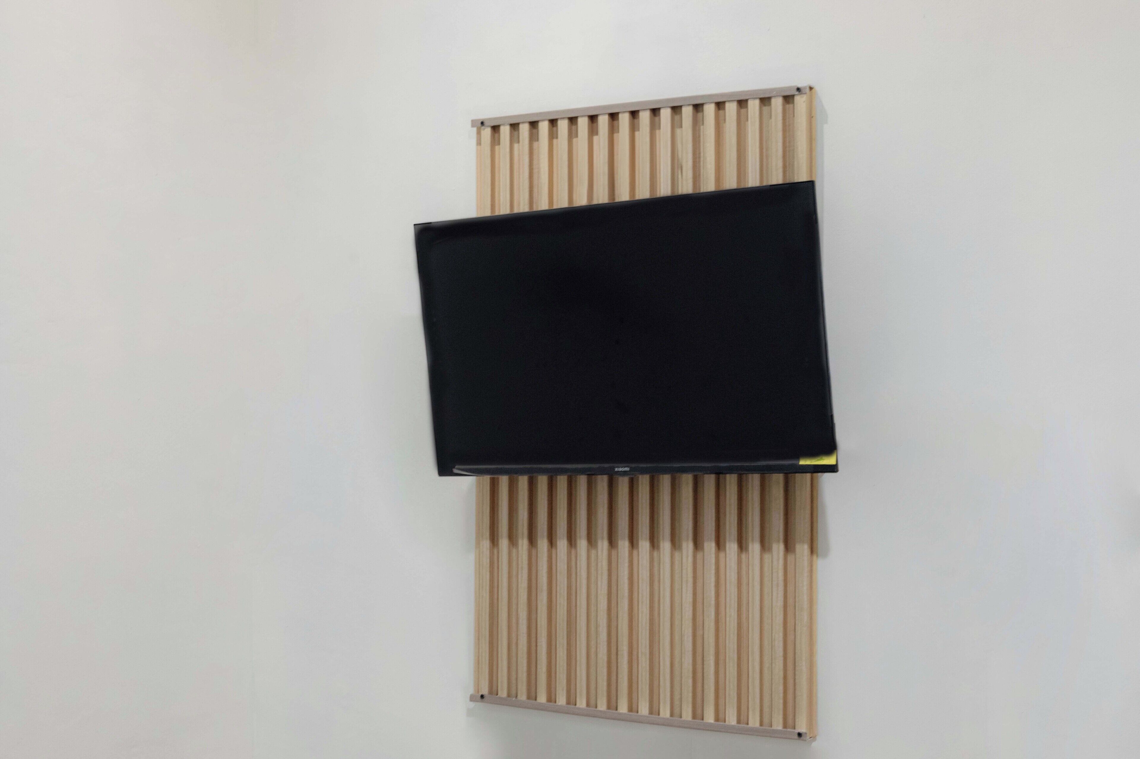 A flat-screen TV mounted on a wall with a wooden slat design.