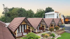 A row of bungalow-style accommodations with pitched roofs, outdoor seating, and a landscaped garden area.