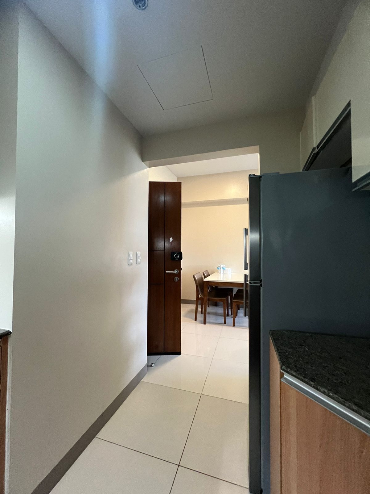A kitchen with a refrigerator, wooden cabinets, and a dining area with a table and chairs.