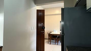 A kitchen with a refrigerator, wooden cabinets, and a dining area with a table and chairs.