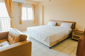 A bedroom with a bed, a chair, a nightstand, and a window with curtains.