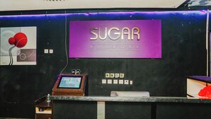 A reception desk with a sign reading "SUGAR Karaoke".