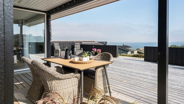 Un terrazzo con mobili in vimini, un tavolo e vista sul mare.