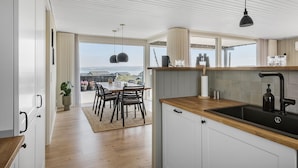 Una cucina moderna con un piano di lavoro in legno, un lavello nero e illuminazione a sospensione.