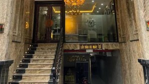 A hotel entrance with a grand staircase, a chandelier, and a sign reading 'ROYAL HOTEL'.