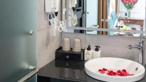 A modern bathroom with a large mirror, a white sink, and a hairdryer mounted on the wall.