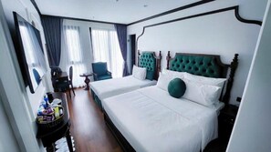 Une chambre d’hôtel avec deux lits, une chaise, une petite table et une fenêtre avec des rideaux.