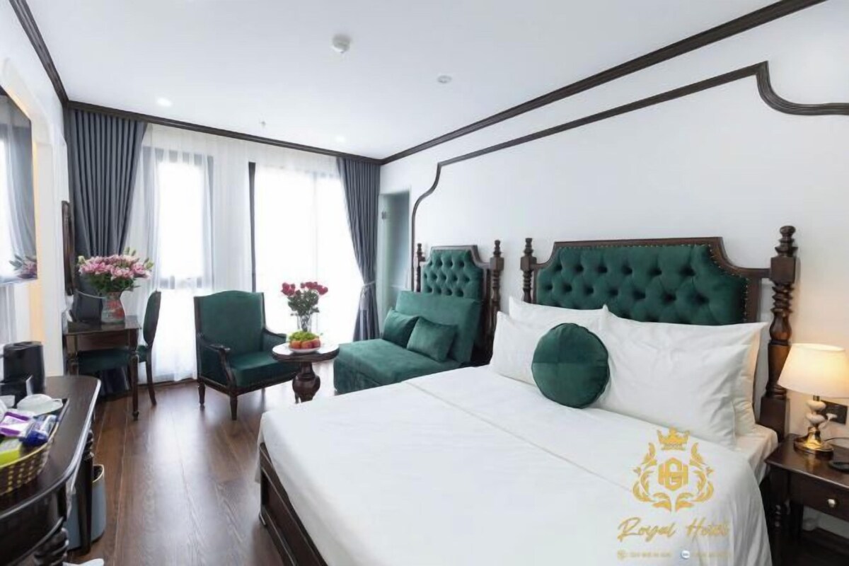 A hotel room with a large bed, a desk, a chair, and a view of the outdoors.