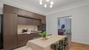 Una cocina moderna con armarios de madera oscura, horno empotrado y comedor con mesa y sillas.