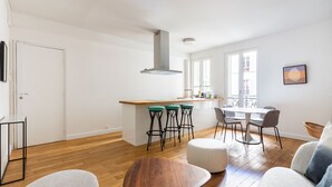 A modern kitchen with a central island, bar stools, and a dining area with chairs.