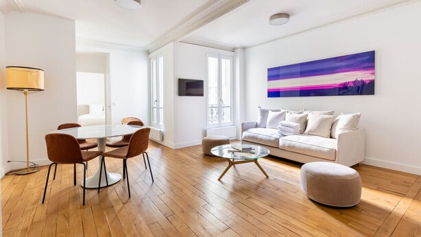 A modern living room with a glass dining table, brown chairs, a white sofa, and a round coffee table. - Eiffel Tower - Renovated 4 people (Paris)