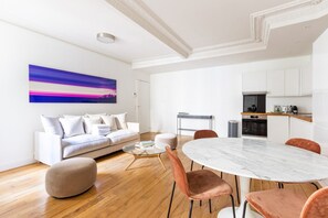 Un salon moderne avec un canapé blanc, une table ronde en marbre et une table basse.