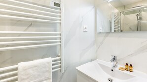Une salle de bain moderne avec un meuble-lavabo blanc, un porte-serviettes et un miroir.
