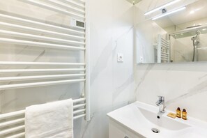 Une salle de bain moderne avec un meuble-lavabo blanc, un porte-serviettes et un miroir.