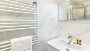 A modern bathroom with a white marble sink, a towel rack, and a mirror. - Eiffel Tower - Renovated 4 people (Paris)