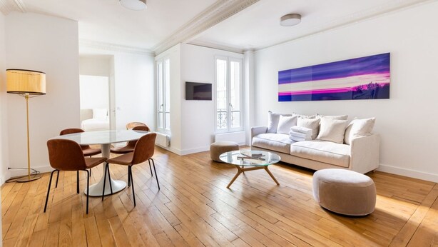 Un salon moderne comprenant un coin repas, un canapé, une table basse et un tableau accroché au mur.