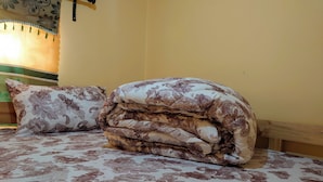 A bed with a patterned bedspread and two pillows, one with a paisley design and another with a floral pattern. - Sero Safaris Hostel (Arusha)