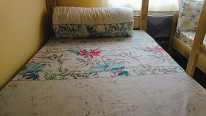 A small, single-bed room with a floral-patterned bedspread and a matching pillow. - Sero Safaris Hostel (Arusha)