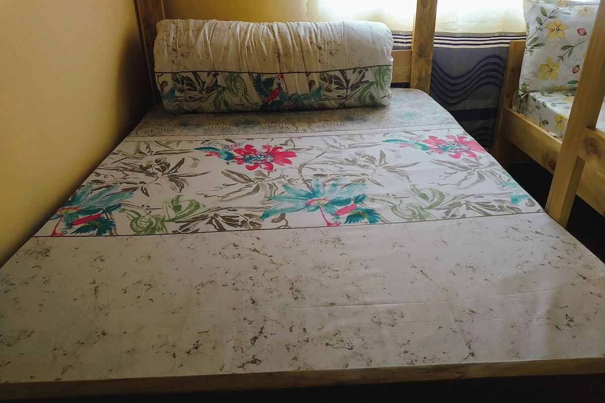 A small, single-bed room with a floral-patterned bedspread and a matching pillow.