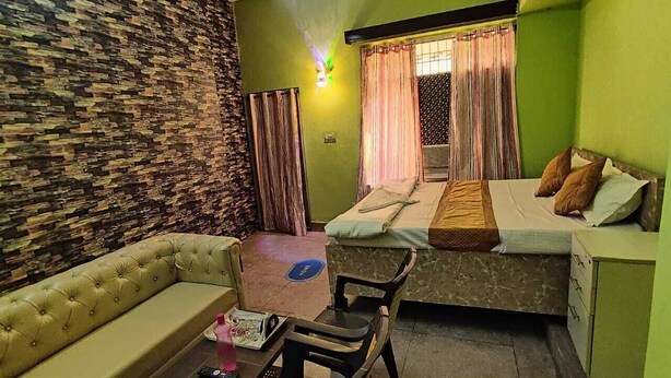 A compact room with a sofa, a small table, a bed with a mattress and pillows, and a nightstand.