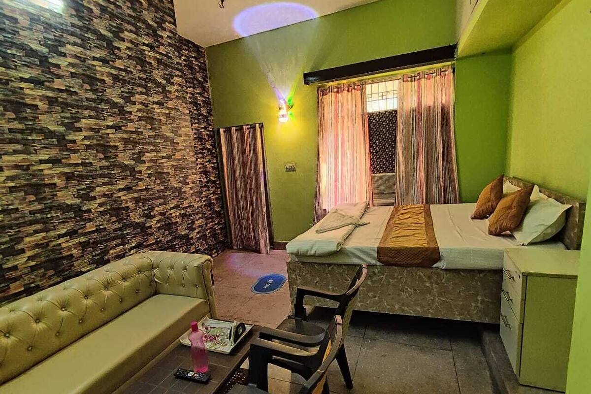 A compact room with a sofa, a small table, a bed with a mattress and pillows, and a nightstand.