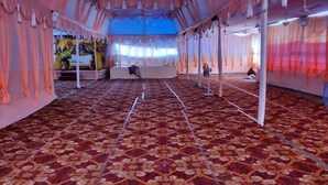 A tented event space with a patterned carpet, draped curtains, and a stage area.