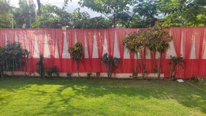 A grassy yard with a red and white fence, potted plants, and trees.