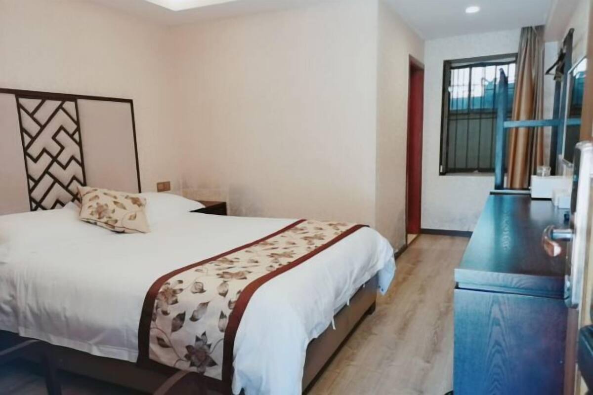 A bedroom with a bed, bedside table, and a dresser.
