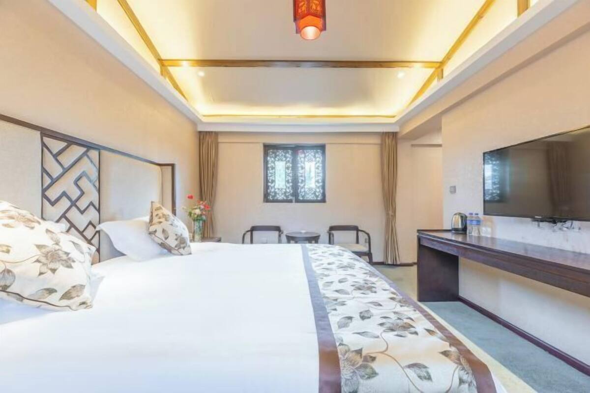 A hotel room with a bed, a desk, a chair, and a window.
