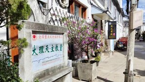 A building with a signboard, a flower pot, and a street view. - Yahve Academy Hotel (Dali City)