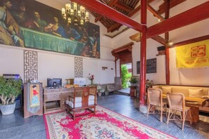 Una habitación tradicional con un gran mural, muebles de madera y una alfombra roja.