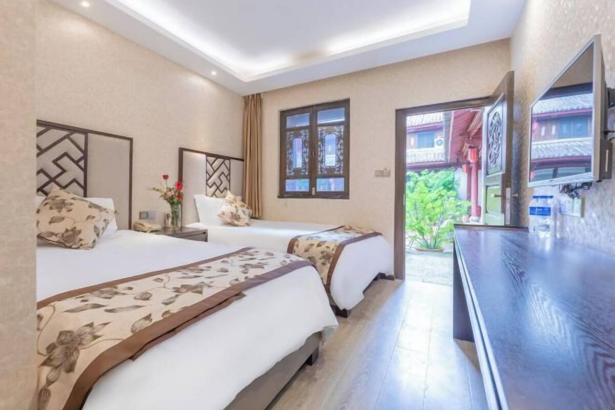 A hotel room with two beds, a large mirror, and a TV.