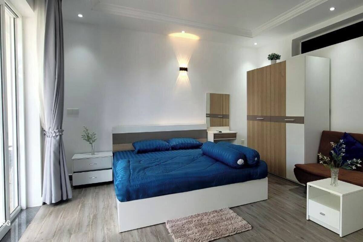 Ein modernes Schlafzimmer mit einem großen Bett, einer Couch, einem Nachttisch und einem Kleiderschrank.