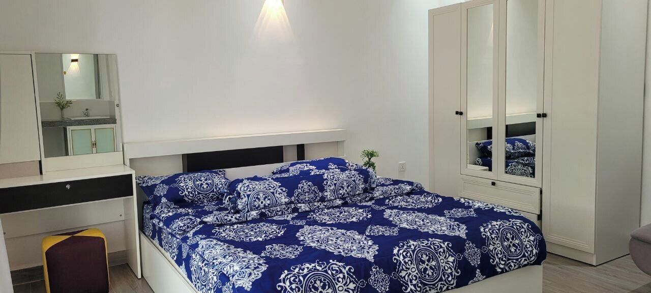Un dormitorio con una cama, un armario, un espejo y una mesita.
