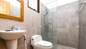 A bathroom with a sink, toilet, and glass-enclosed shower. - Maharani Guest House (Yogyakarta)