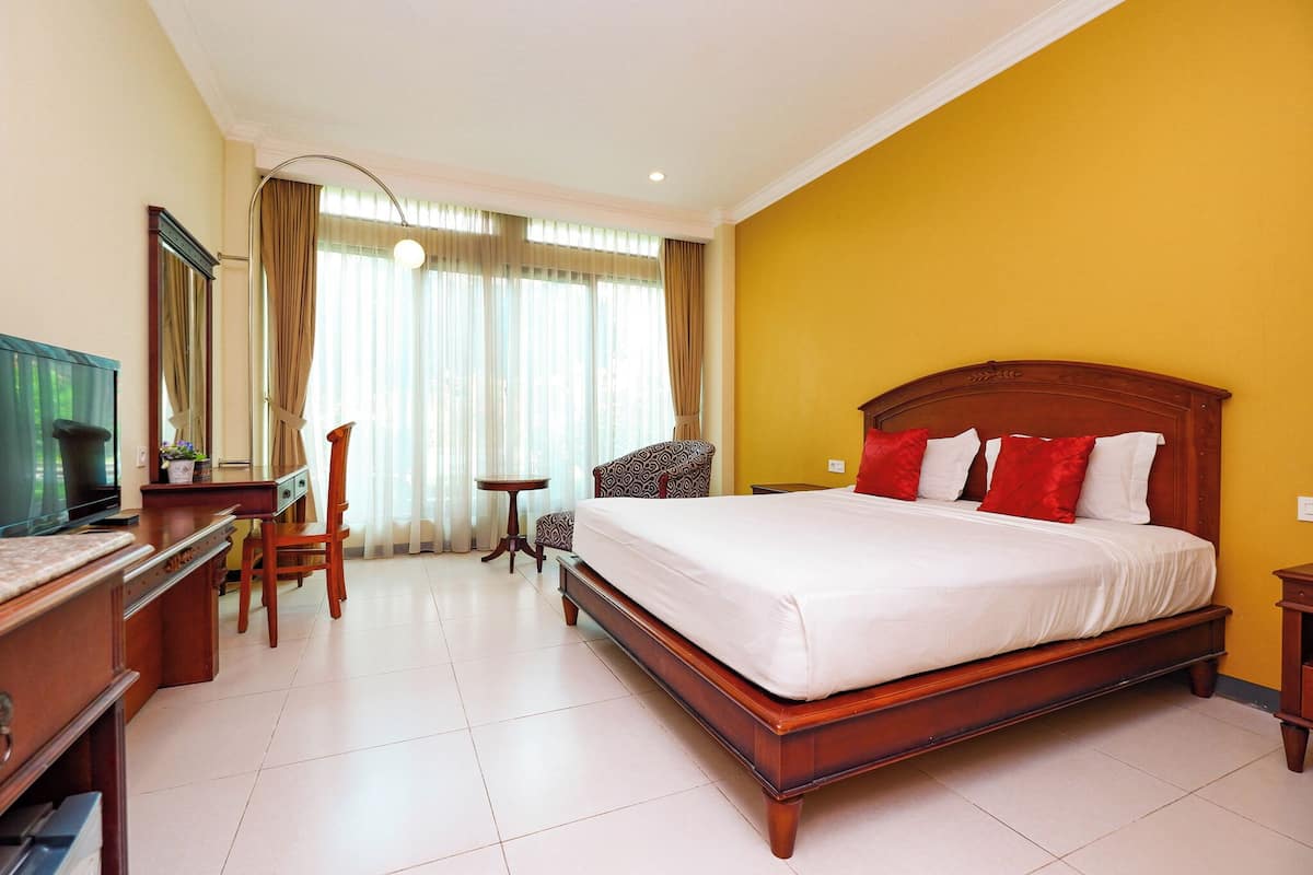 Una habitación de hotel con una cama grande, un escritorio, una silla y un televisor.