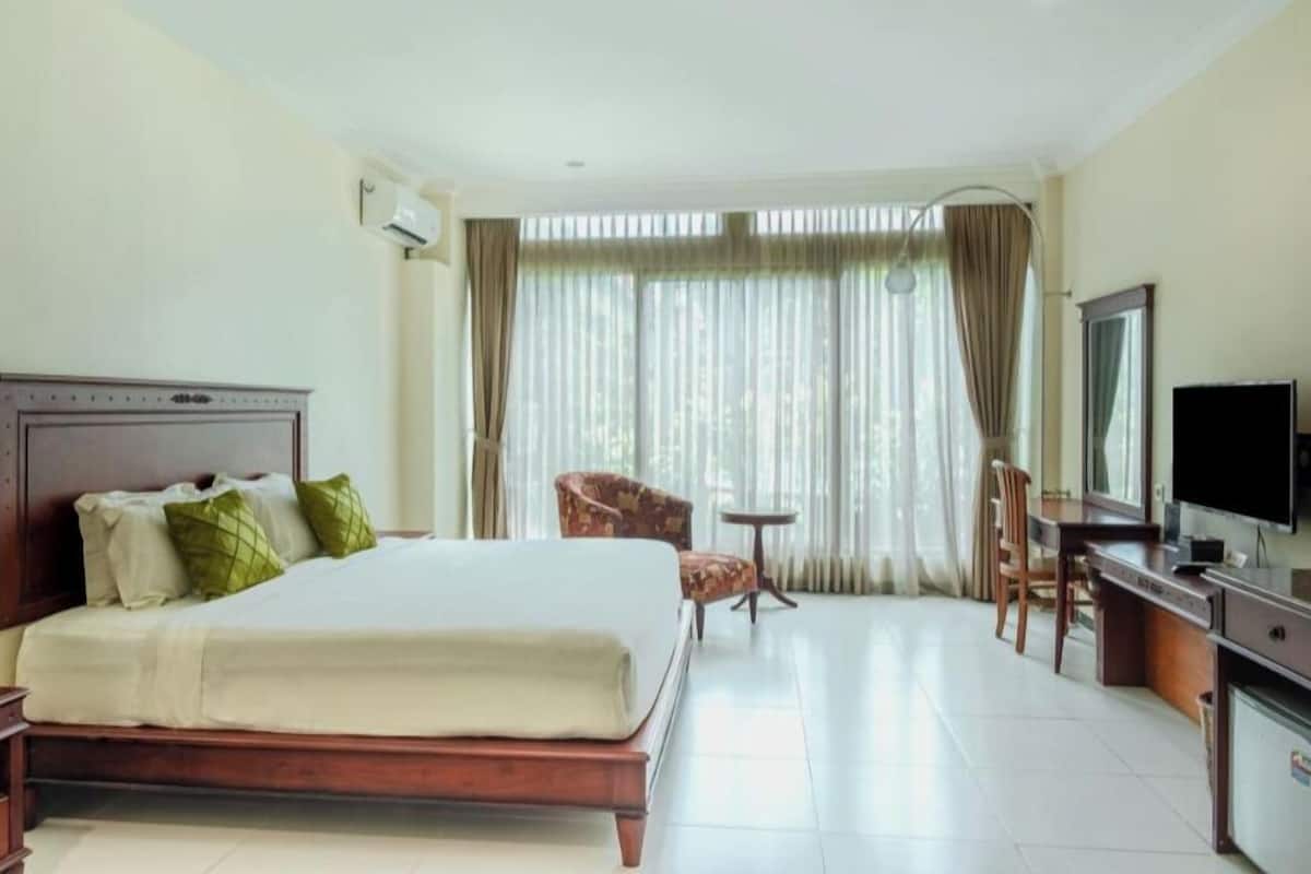 Habitación de hotel con una cama grande, un escritorio con computadora, una silla y un televisor.