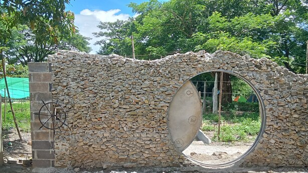 A stone wall with a circular opening. - Backpackers Temple  (Mae Sot)
