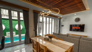 Una sala de estar moderna con una mesa de comedor, sofá y un televisor mostrando 'NETFLIX'.