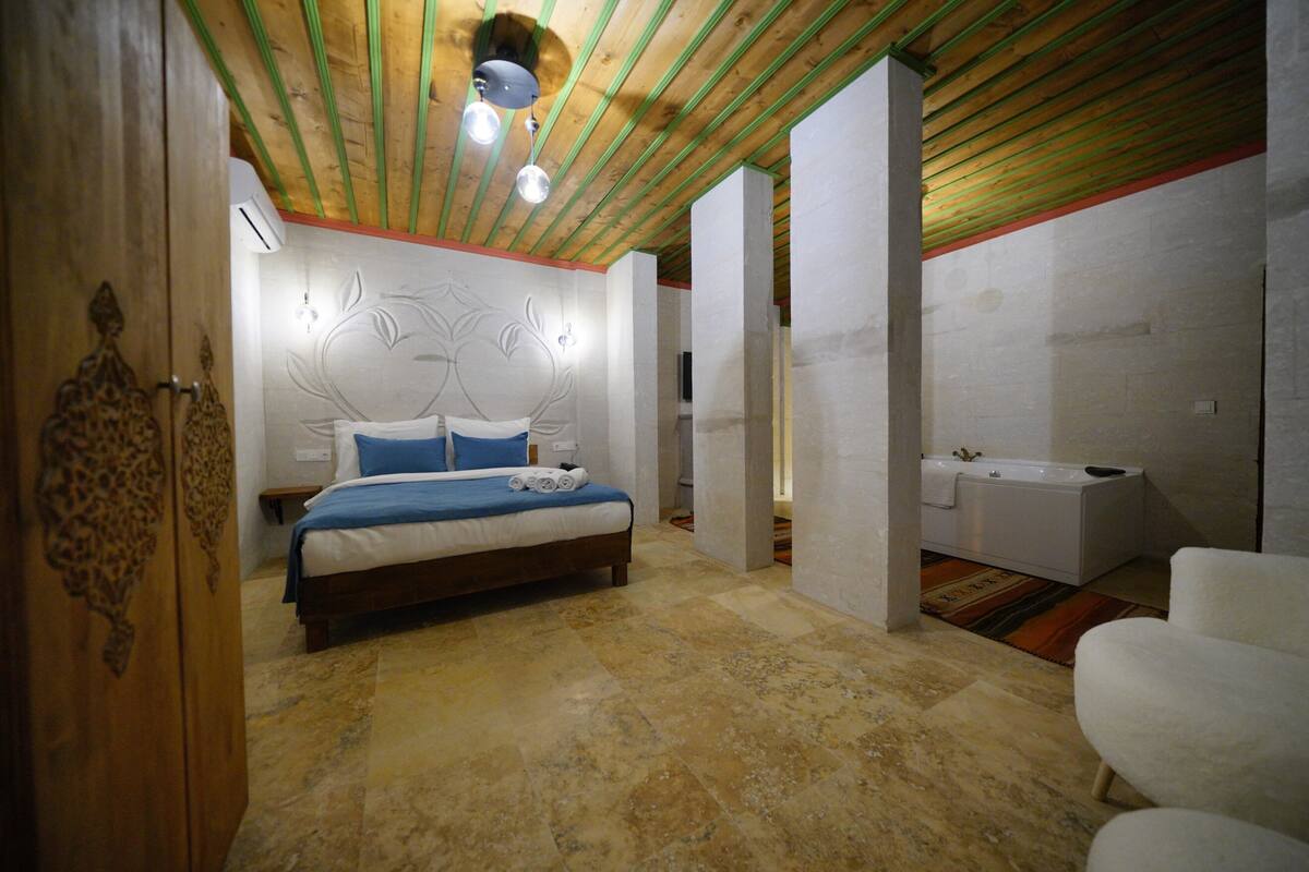 Un dormitorio con cama, un baño con bañera y techo de madera.