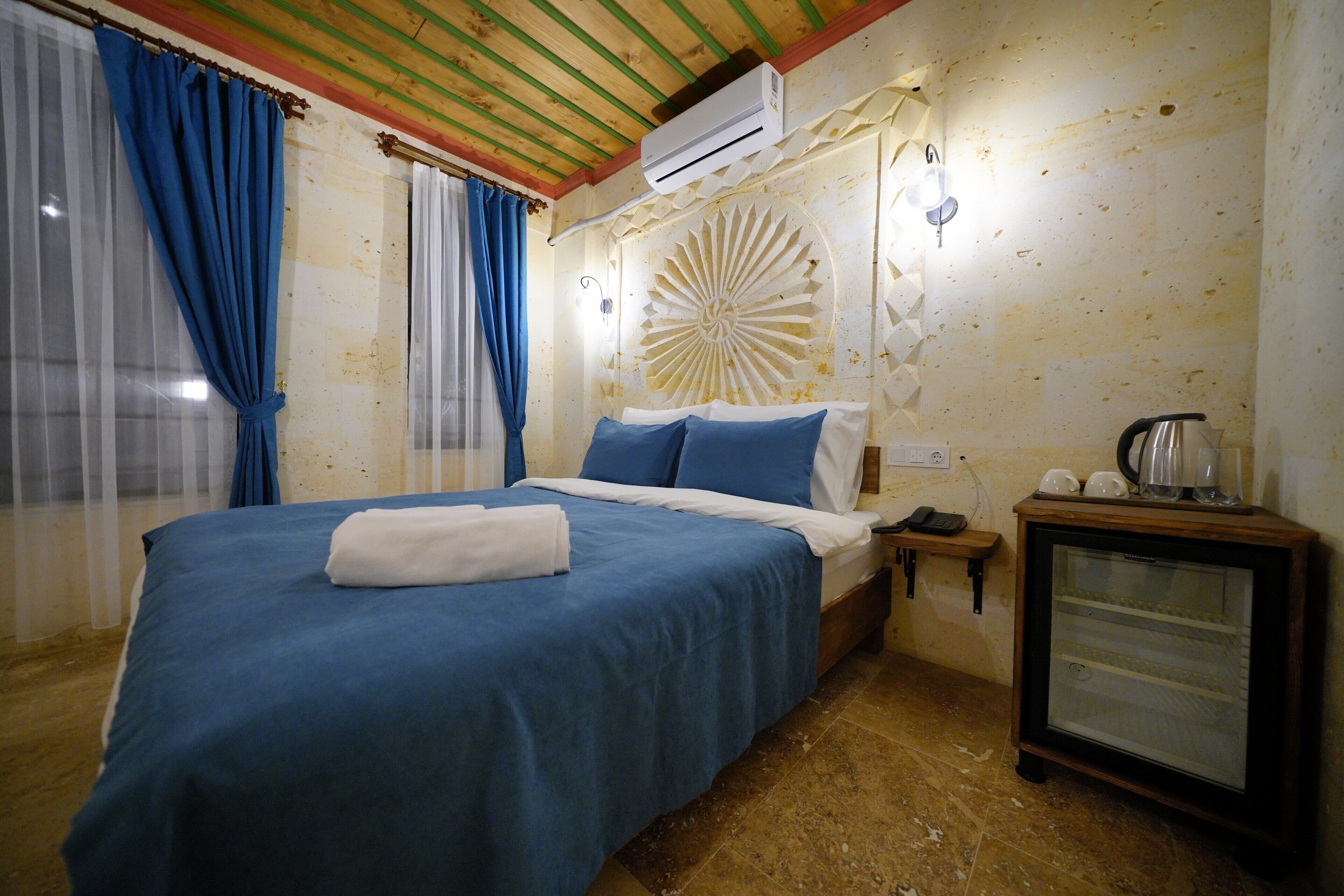 Un dormitorio con cama, cortinas, un reloj de pared y una mesita con una tetera.