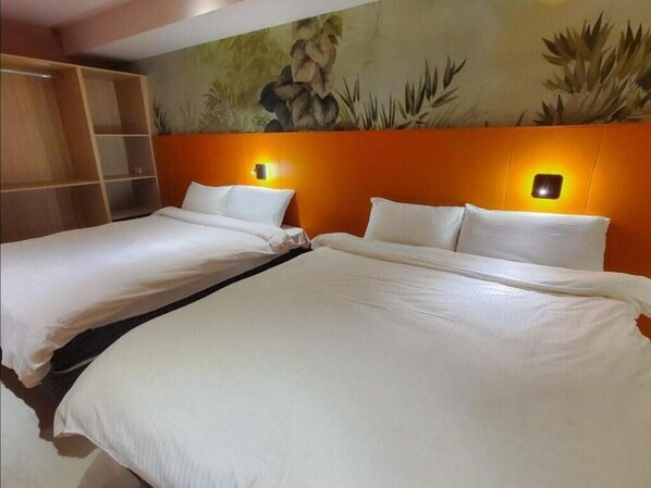 Une chambre d’hôtel avec deux lits, chacun agrémenté de draps et d’oreillers blancs, et une fresque murale au-dessus des lits.