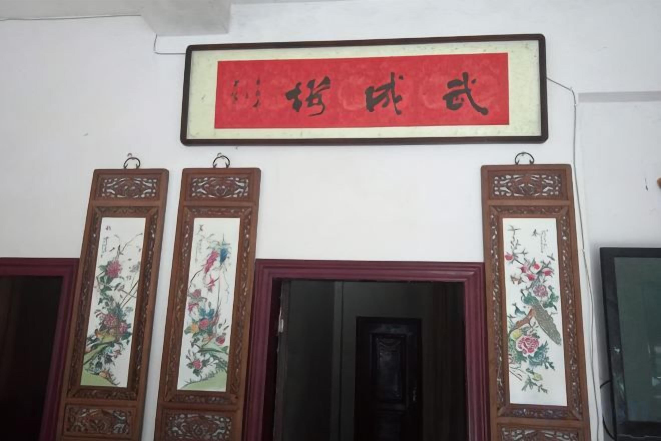 A room with a red framed sign, two doors with floral designs, and a window.