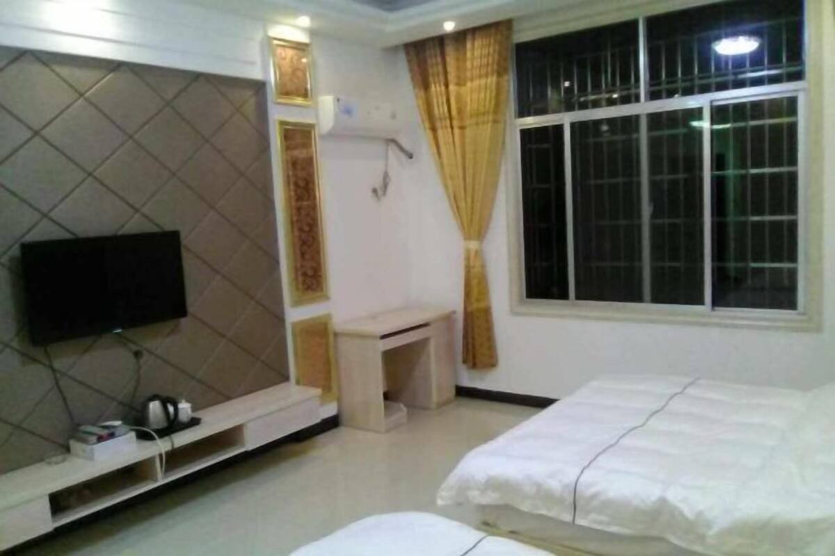 A hotel room with a bed, a TV, a desk, and a window.